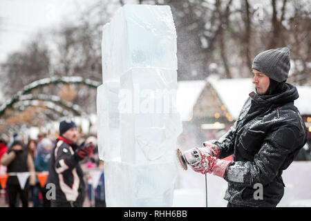 Ukraine, Lviv - Januar 11, 2019: Master macht Eis Skulpturen aus Eis. Der Bildhauer Schnitte eis Konturen aus Eis mit einer Kettensäge Stockfoto