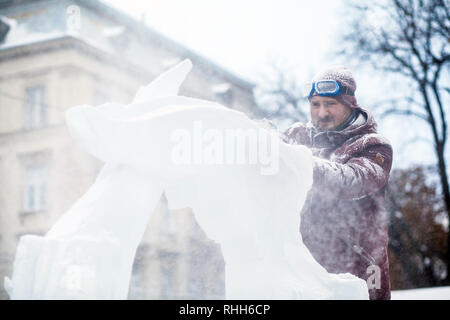 Ukraine, Lviv - Januar 11, 2019: Master macht Eis Skulpturen aus Eis. Der Bildhauer Schnitte eis Konturen aus Eis mit einer Kettensäge Stockfoto