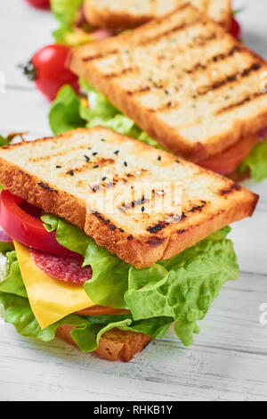 Drei Sandwiches mit Schinken, Salat und frisches Gemüse auf weißem Hintergrund Stockfoto