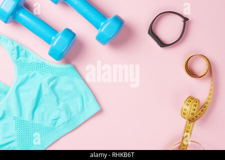 Sport-BH, Kurzhanteln, Maßband und fitness Tracker auf rosa Hintergrund, Ansicht von oben mit der Kopie. Fitness und Body Care Konzept Stockfoto