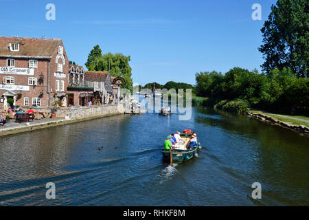 Leute auf einem kleinen Motorboot entlang dem Fluss Frome reisen. Gebäude am Kai, Wareham, Dorset UK, gehören der alte Getreidespeicher, Cafe und Bar. Stockfoto