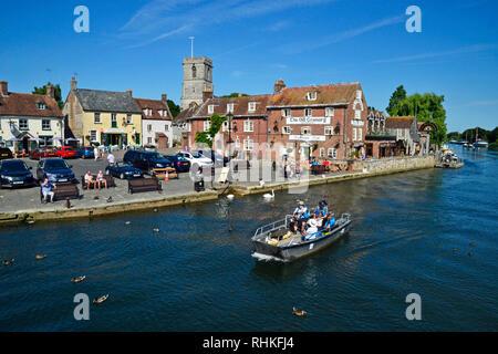 Leute auf einem kleinen Motorboot entlang dem Fluss Frome reisen. Gebäude am Kai, Wareham, Dorset UK, gehören der alte Getreidespeicher, Cafe und Bar. Stockfoto