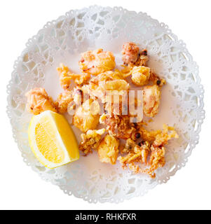 Chipirones, zerschlagenen Gebratene baby Tintenfisch mit Zitrone auf weiße Platte serviert. Auf weissem Hintergrund Stockfoto