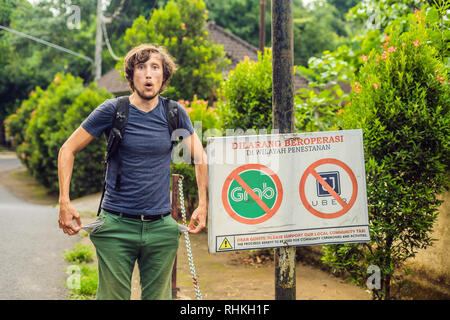 BALI, Indonesien - 21. Mai, 2018: Der junge Mann sieht Protest Zeichen an der Wand in der Indonesischen Uber und Taxifahrer Greifer Einwand lautet "Uber und Greifer Stockfoto