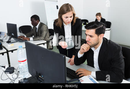 Unglückliche Menschen Manager bei Laptop und wütenden weiblichen Boss pointinting zu vermisst in Arbeit Stockfoto