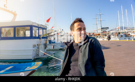 Junge türkische touristische Mann bei Sonnenuntergang im Yachthafen von Bodrum, Türkei lächelnd. Segelboote, Sailor, und klaren Tagen Stockfoto