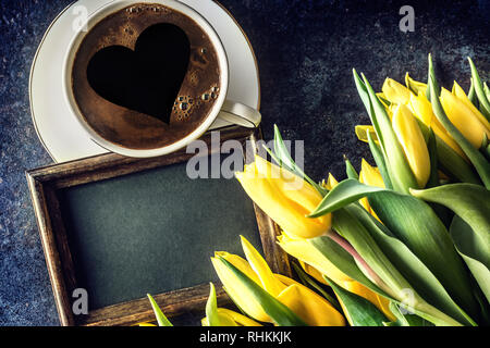 Oben auf Ansicht cup Form Kaffee mit Herz leere Schiefertafel und Frühling Tulpen auf hölzernen Tisch. Stockfoto