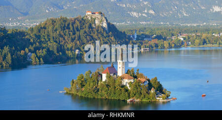 Blick auf die Kirche der Himmelfahrt auf Blejski Otok mit Burg von Bled, Bled, Bled, Gorenjska, Slowenien. Stockfoto