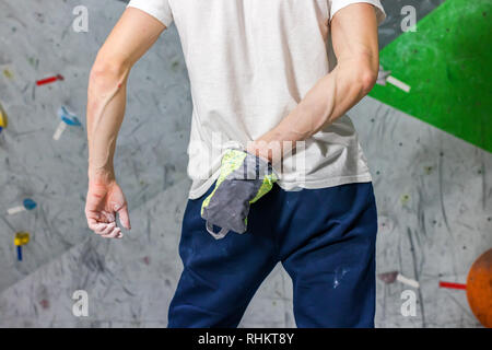 Kletterer Mann schob seine Hände in eine Tasche von Magnesia Pulver hinter seinem Rücken in der Boulder Halle Stockfoto