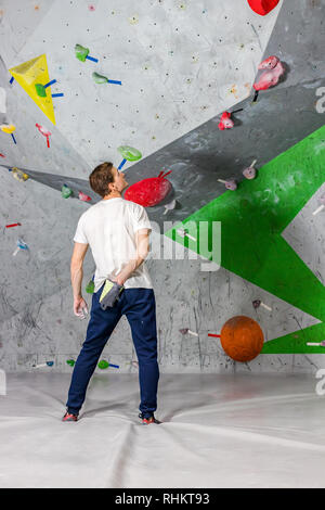 Kletterer Mann schob seine Hände in eine Tasche von Magnesia Pulver hinter seinem Rücken in der Boulder Halle Stockfoto