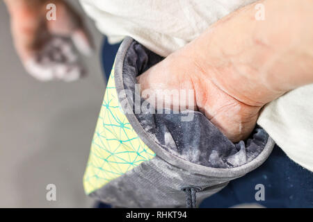 Kletterer Mann schob seine Hände in eine Tasche von Magnesia Pulver hinter seinem Rücken in der Boulder Halle Stockfoto