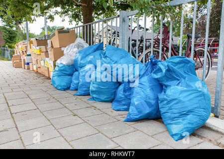 Blaue Müllsäcke und Boxen mit Abfällen stehen auf niederländischen Fußweg Stockfoto