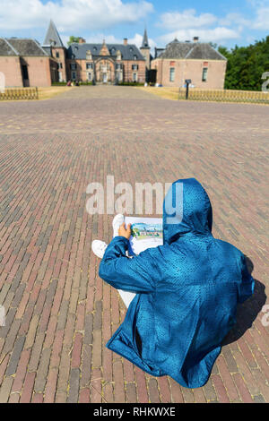 Teenager in der blauen Jacke sitzen auf der Straße malen Schloss Stockfoto