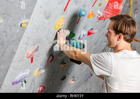 Die zwei weißen Mann sind die Hände auf dem ovalen passive Haken der Kletterwand gehalten Stockfoto