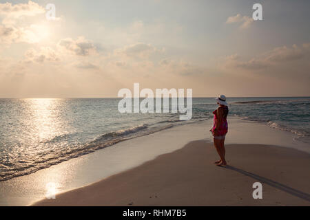 Malediven Urlaub - eine Frau touristische Blick auf den Sonnenuntergang über dem Indischen Ozean vom Strand, Konzept - Spielraum; Rasdhoo Atoll, Malediven Asien Stockfoto