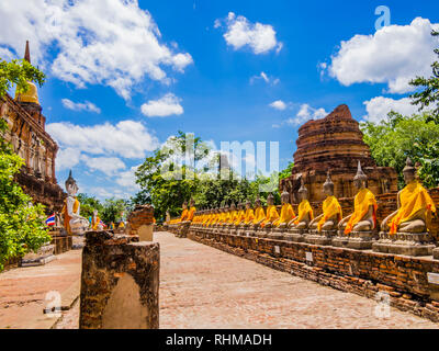 Thailand, beeindruckende Reihe von Buddha Statuen mit orange Tuniken in Ayutthaya alte Tempel Stockfoto