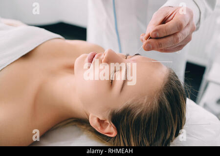 Acupuncturist Einführen einer Nadel in ein weibliches Gesicht Stockfoto