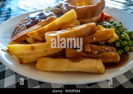 Nahaufnahme von frisch gekochten chunky Pommes mit Soße auf Chips auf einem karierten Tischtuch in einem Cafe in Doncaster, Yorkshire, England Stockfoto