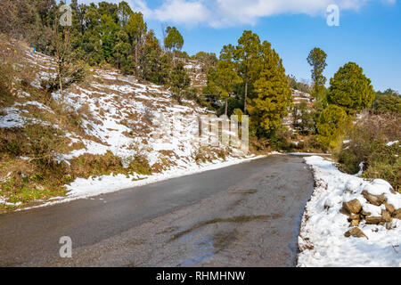 Landschaftlich reizvolle Straße durch das Tal von banikhet Dalhousie Himachal Pradesh mit Schnee Berge und Bäume abgedeckt. Bergauf scenic road winter Reisen c Stockfoto