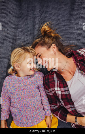 Mutter und Tochter liegend auf der Decke mit ihren Köpfen berühren und lächelnd. Mutter, eine tolle Zeit zusammen mit ihrer Tochter im Freien. Nach oben V Stockfoto