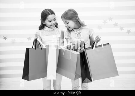 Einkaufen mit beste Freundin Konzept. Mädchen wie einkaufen. Die Kinder glücklich kleine Mädchen halten Einkaufstaschen. Viel Spaß beim Shoppen mit der besten Freundin oder Schwester. Mädchenhafte Glück. Die Kinder glücklich tragen Bündel Pakete. Stockfoto