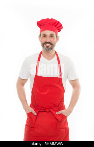 Ich sauber und für Sie kochen. Reife bärtige Mann in Chef hat und Schürze. Senior Kochen mit Bart und Schnurrbart tragen Latzschürze. Reifen chief Cook in rot Kochschürze. Home Kochen. Stockfoto