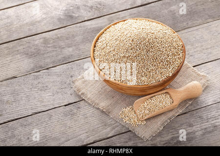 Quinoa Samen in Keramik Schüssel und Schaufel auf hölzernen Tisch Stockfoto