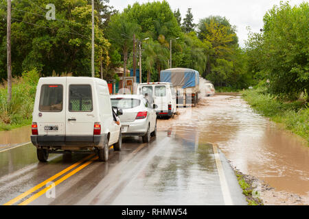 Eine Linie der Datenverkehr einer überschwemmten Bereich der Straße, in der Hoffnung es passierbar ist. Bild auf der Route 68, in der Nähe von El Carril, Provinz Salta, Argentinien. Stockfoto