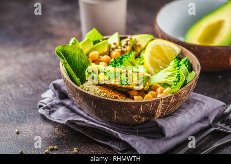 Veganes Mittagessen in einer Kokosnuss Schale: grün Burger mit Salat und Kichererbsen. Gesunde vegane Ernährung Konzept. Stockfoto
