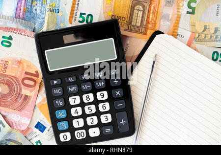 Taschenrechner mit Euro Banknoten und Münzen im Hintergrund Stockfoto