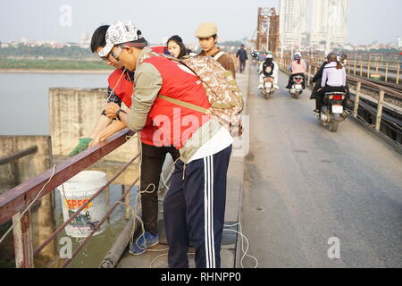 Hanoi, Vietnam. 28 Jan, 2019. Menschen sind Freigabe Goldfische aus einem Eimer in den Roten Fluß. Es wird angenommen, dass eine Freigabe der Fisch für das Neue Jahr viel Glück bringen. (Dpa' Goldfisch für Jade Kaiser: Religiöse Rituale sind dauerhafte in Vietnam" vom 04.02.2019) Credit: Bennett Murray/dpa/Alamy leben Nachrichten Stockfoto