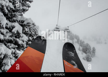 Ski Sessellift bringt Skifahrer und Snowboarder auf den Berg bei starkem Schneefall auf einem nebligen Wintertag in Courchevel, Frankreich. Stockfoto