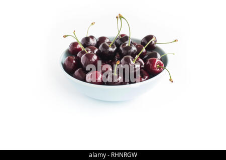 Nahaufnahme einer blaue Schale mit frischen Kirschen auf weißem Hintergrund gefüllt. Schrägansicht. Stockfoto