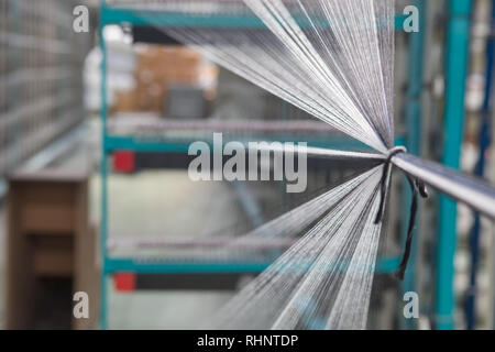 Nahaufnahme Makro Detail von Garn thread Linien, die in der Webmaschine Webstuhl. Garne Spulen in einer Textilfabrik. Stockfoto