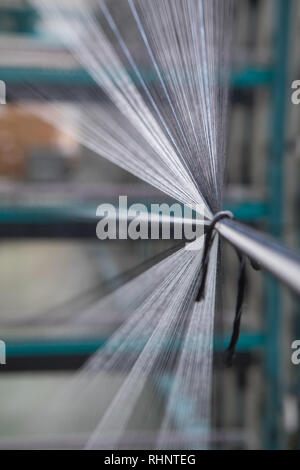 Nahaufnahme Makro Detail von Garn thread Linien, die in der Webmaschine Webstuhl. Garne Spulen in einer Textilfabrik. Stockfoto