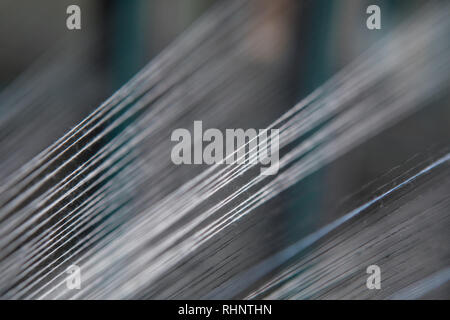 Nahaufnahme Makro Detail von Garn thread Linien, die in der Webmaschine Webstuhl. Garne Spulen in einer Textilfabrik. Stockfoto