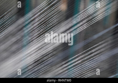 Nahaufnahme Makro Detail von Garn thread Linien, die in der Webmaschine Webstuhl. Garne Spulen in einer Textilfabrik. Stockfoto