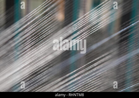 Nahaufnahme Makro Detail von Garn thread Linien, die in der Webmaschine Webstuhl. Garne Spulen in einer Textilfabrik. Stockfoto