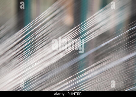 Nahaufnahme Makro Detail von Garn thread Linien, die in der Webmaschine Webstuhl. Garne Spulen in einer Textilfabrik. Stockfoto