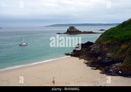 Mann an Segelboot Günstig in Belvoir Strand Blick von der Küste weg auf die Insel Herm, Channel Islands.de. Stockfoto