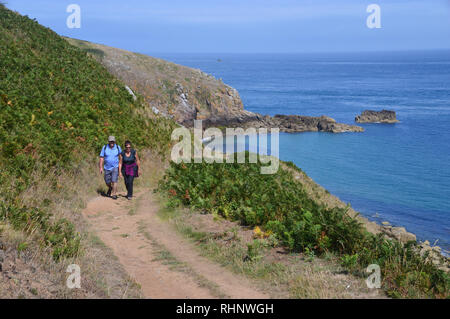 Ein paar Wanderer Wandern im Sonnenschein an der Küste entlang in Richtung Rosiere Schritte auf Herm Insel, Channel Islands.de. Stockfoto