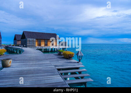 Schönen tropischen vibrant Beach View mit über Wasser Bungalows, in einem Luxus Resort mit bunten Himmel, Stockfoto