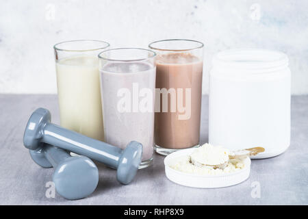 Protein Cocktails, Protein Pulver und Hantel. Vanille-, Beeren und Schokolade Protein Shakes. Sport Ernährung und gesunde Lebensweise. Stockfoto