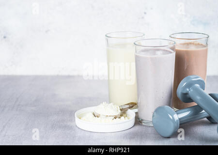 Protein Cocktails, Protein Pulver und Hantel. Vanille-, Beeren und Schokolade Protein Shakes. Sport Ernährung und gesunde Lebensweise. Stockfoto