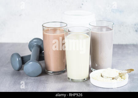 Protein Cocktails, Protein Pulver und Hantel. Vanille-, Beeren und Schokolade Protein Shakes. Sport Ernährung und gesunde Lebensweise. Stockfoto