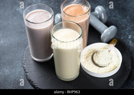 Fitness Concept, Sport Ernährung. Protein Cocktails, Protein Pulver und Hantel. Vanille-, Beeren und Schokolade Protein Shakes. Stockfoto