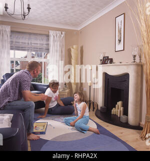 Eltern und kleine Mädchen entspannen im Wohnzimmer EDITORIAL NUR VERWENDEN Stockfoto