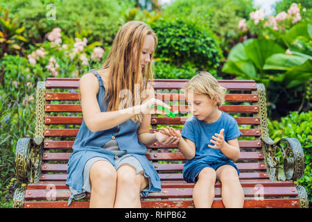 Mutter und mit Waschen Handdesinfektionsmittel gel im Park vor einem Snack Sohn Stockfoto