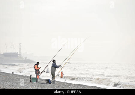 Zwei angler angeln für Kabeljau auf einem Januar Tag mit einer rauhen Meer weg Rossall Strand Stockfoto