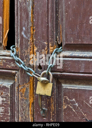 Eine marode und defekten Tür mit Fading malen. Eine Kette hält die Tür zusammen mit zwei Vorhängeschlösser. Stockfoto